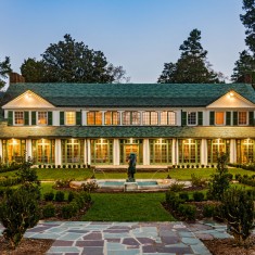 The front of Reynolda House at sundown with lights on inside the building.