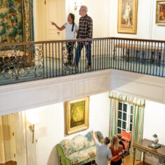 People observing and pointing at artwork located inside the historic house.