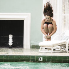 Young lady doing a cannon ball into the historic pool.